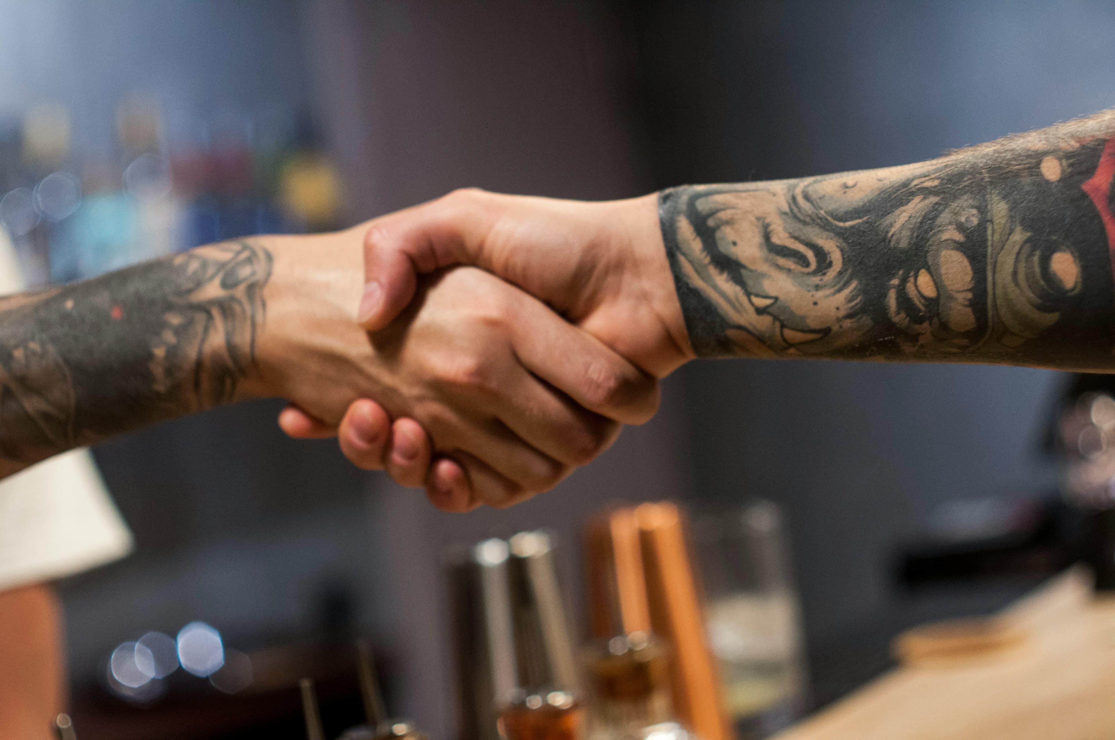 Two tattooed artists shaking hands